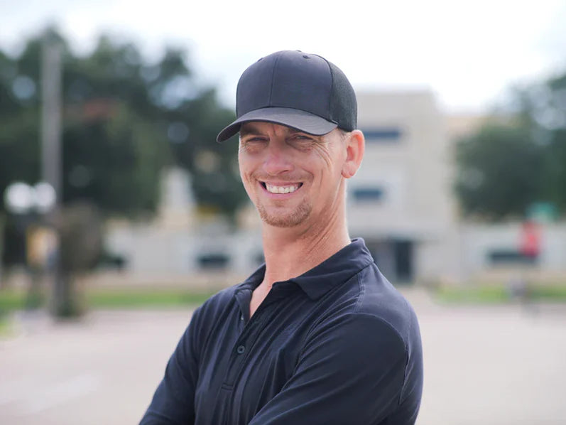 Lance Lockhart - outside sales rep, wearing a black cap and shirt with a logo, standing outdoors.