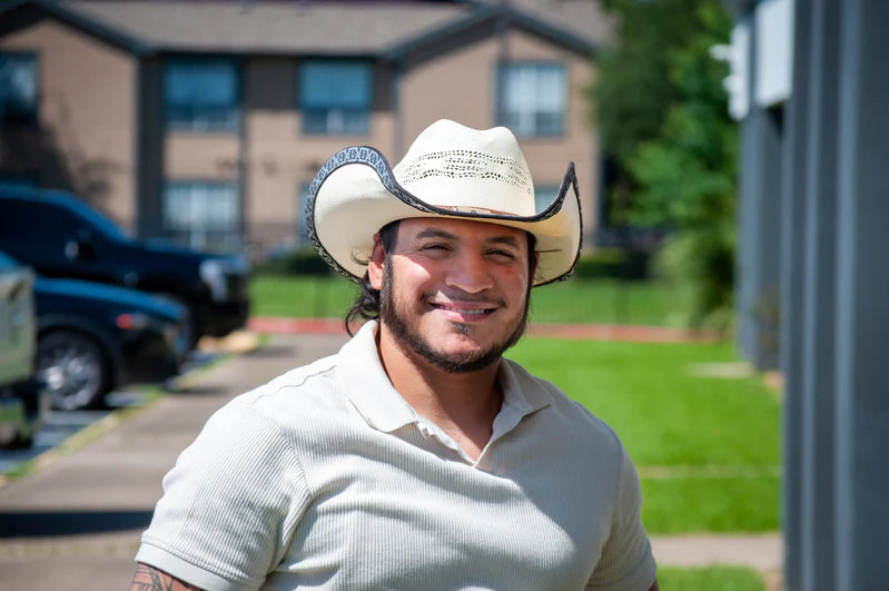 Michael Huron smiling - wearing a cowboy hat outside.